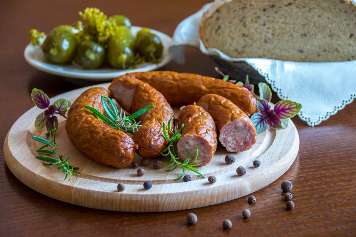 Sausages in natural casing, sliced and served on a wooden board