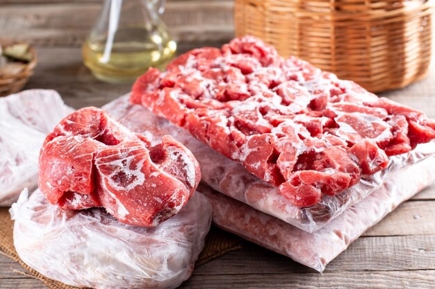 Frozen pork portions, bagged and stacked on a wooden counter