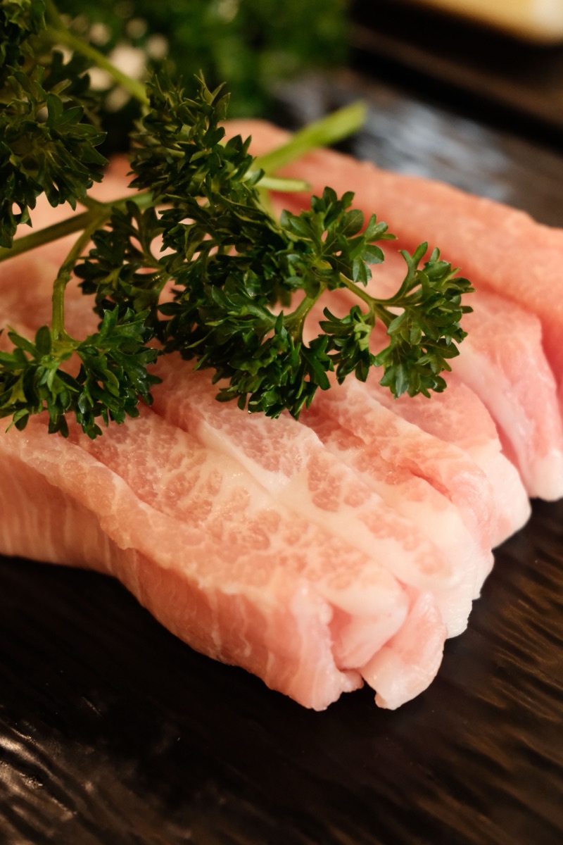 Thinly sliced marbled pork arranged on a dark serving plate