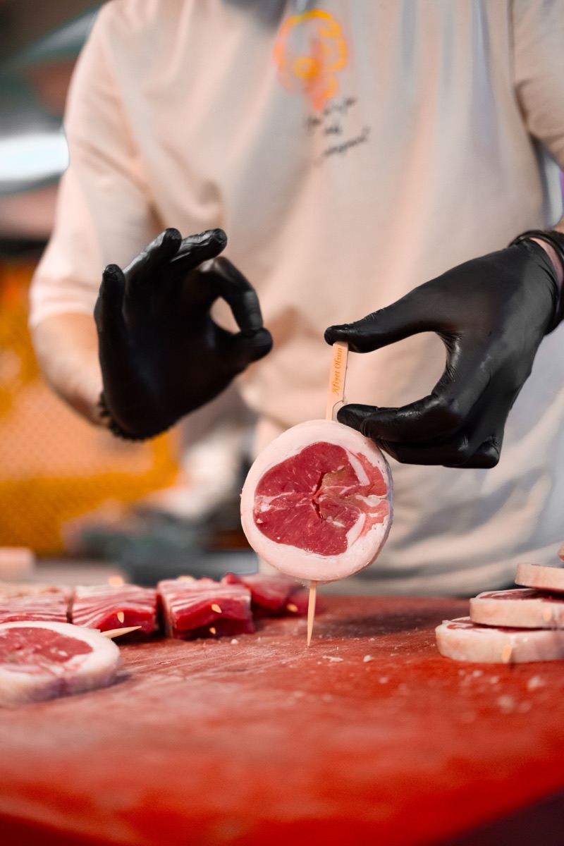 A butcher in gloves portioning meat at a processing table